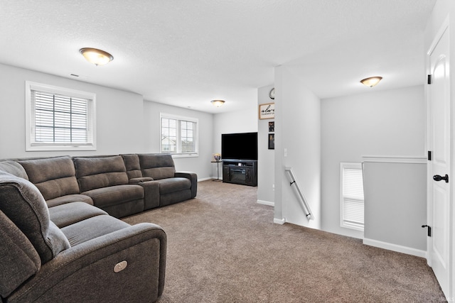 living area with visible vents, baseboards, a textured ceiling, and carpet flooring