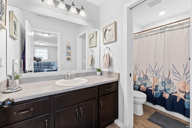 ensuite bathroom with visible vents, vanity, wood finished floors, and ensuite bathroom