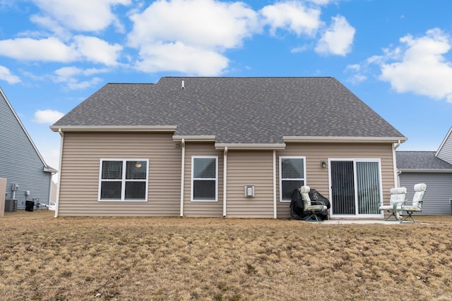 rear view of house with a lawn and roof with shingles