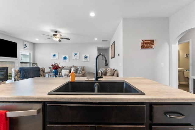 kitchen featuring a tiled fireplace, a sink, open floor plan, light countertops, and dishwasher