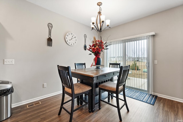 dining area featuring dark wood finished floors, a notable chandelier, baseboards, and visible vents