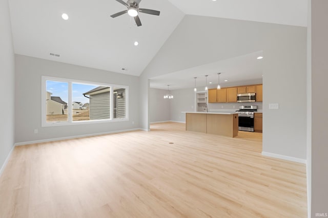 unfurnished living room featuring visible vents, high vaulted ceiling, ceiling fan with notable chandelier, light wood-style floors, and baseboards