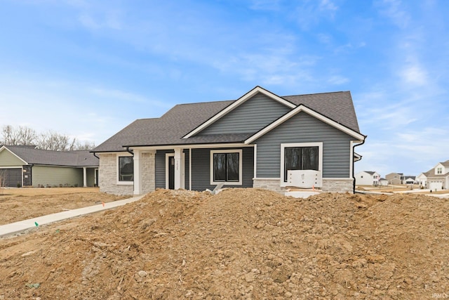 view of front facade featuring stone siding and roof with shingles