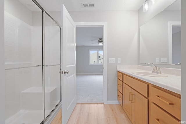 full bath featuring visible vents, vanity, wood finished floors, and a shower stall