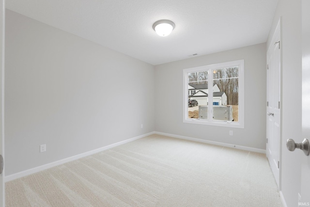 spare room featuring baseboards and light carpet