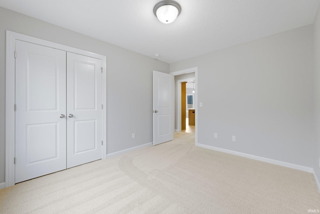 unfurnished bedroom featuring light colored carpet, baseboards, and a closet