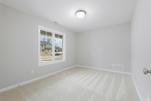 unfurnished room with light carpet, visible vents, and baseboards