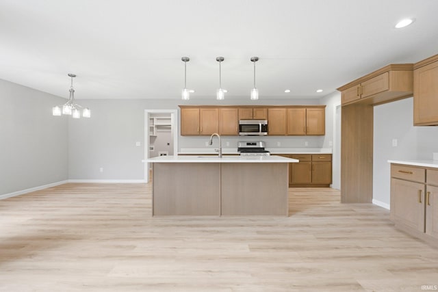 kitchen with pendant lighting, appliances with stainless steel finishes, and light countertops