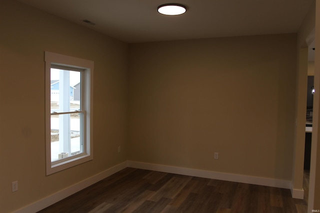 empty room with baseboards and dark wood-type flooring