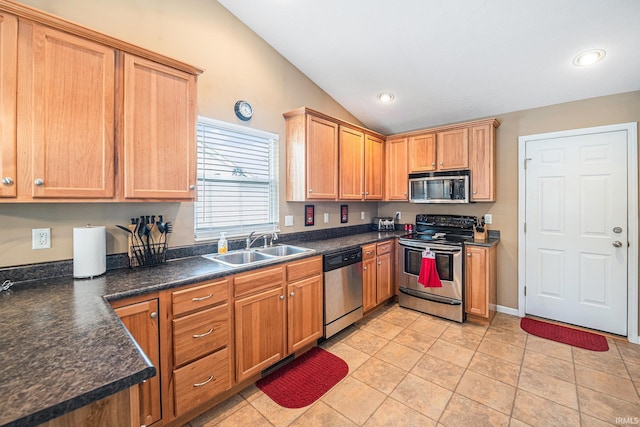 kitchen with dark countertops, stainless steel appliances, lofted ceiling, and a sink