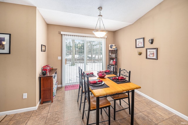 dining area featuring light tile patterned floors, baseboards, and a textured ceiling