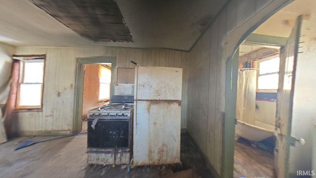 kitchen featuring arched walkways, gas range, and wood walls