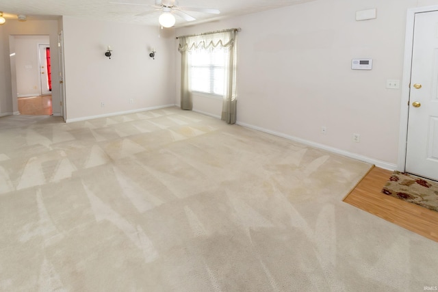 unfurnished living room with light colored carpet, baseboards, and ceiling fan