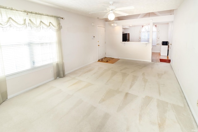 carpeted empty room featuring baseboards and a ceiling fan