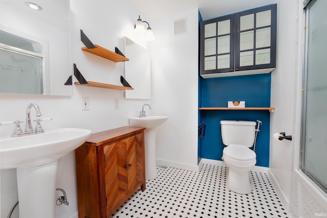 full bath featuring visible vents, toilet, baseboards, and a shower with shower door