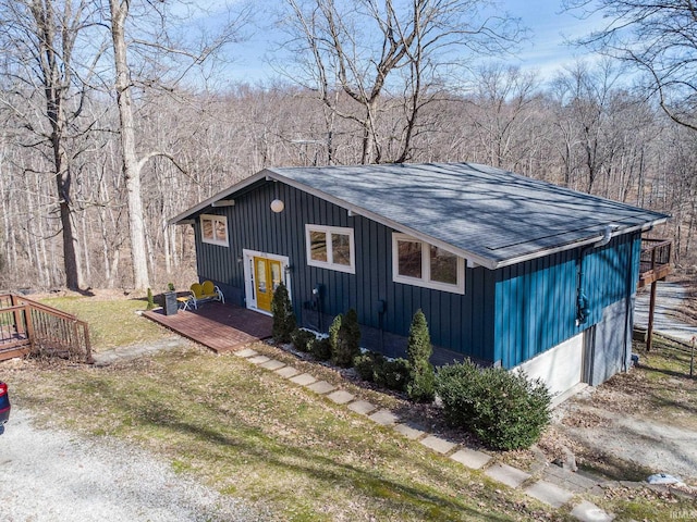 view of front facade with a deck, a front yard, french doors, and a shingled roof