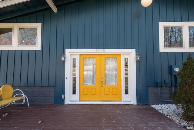 entrance to property with french doors, board and batten siding, and a wooden deck