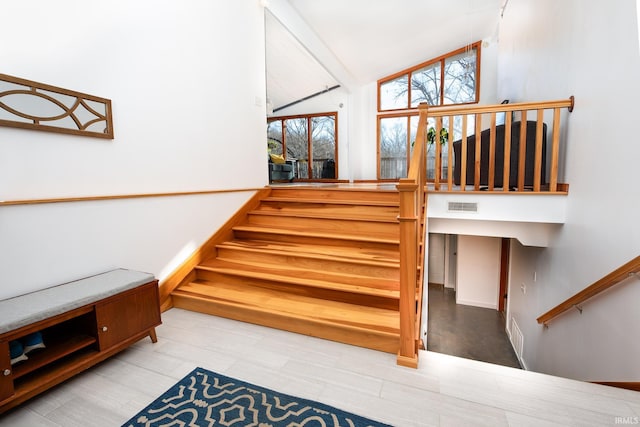 staircase with lofted ceiling, wood finished floors, and visible vents