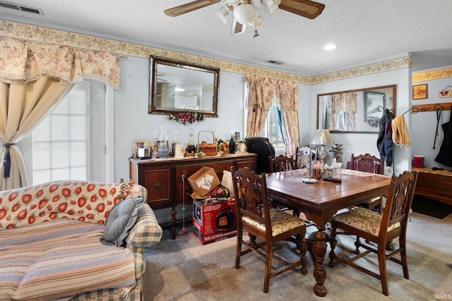 dining space with light carpet, visible vents, a textured ceiling, and a ceiling fan