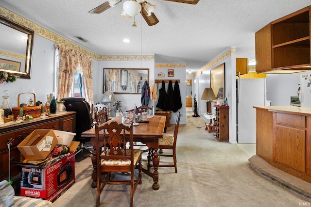 dining area featuring visible vents, light colored carpet, a textured ceiling, and ceiling fan