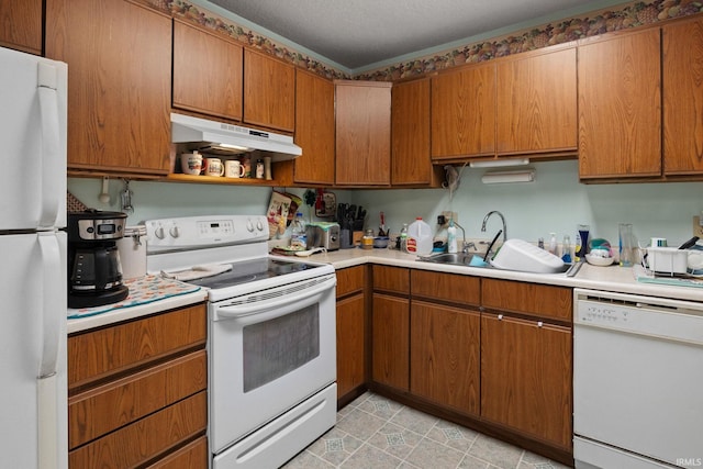 kitchen featuring under cabinet range hood, white appliances, light countertops, and a sink