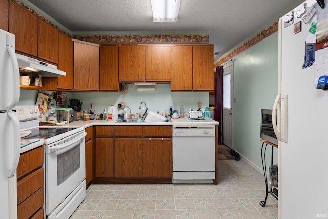 kitchen featuring under cabinet range hood, light countertops, brown cabinetry, white appliances, and a sink