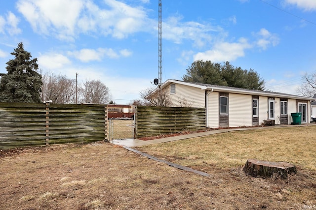 back of house featuring a gate, a lawn, and fence