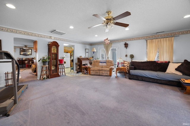 carpeted living room with a ceiling fan, visible vents, and a textured ceiling