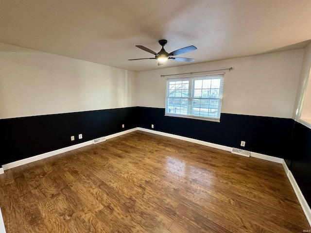 spare room featuring ceiling fan, visible vents, wood finished floors, and wainscoting