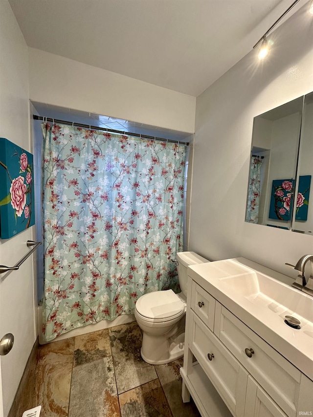 bathroom with stone finish flooring, toilet, vanity, and shower / bath combination with curtain