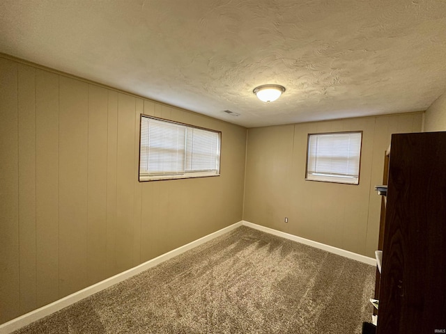 carpeted spare room with visible vents, a textured ceiling, and baseboards