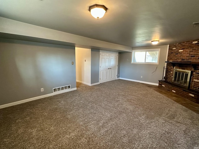below grade area featuring dark colored carpet, visible vents, baseboards, and a fireplace