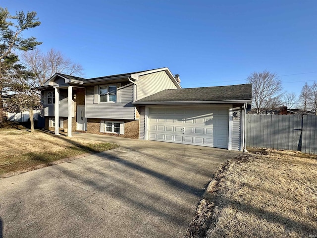 view of front facade featuring brick siding, an attached garage, fence, a chimney, and driveway