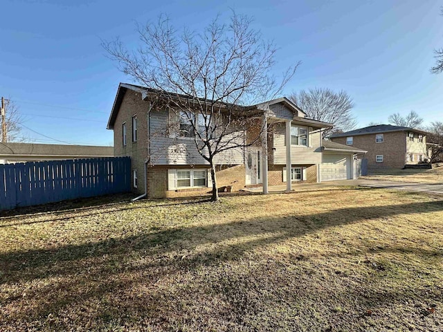 back of property featuring a garage, fence, brick siding, and driveway