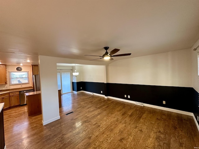 unfurnished room with ceiling fan, visible vents, baseboards, and wood finished floors