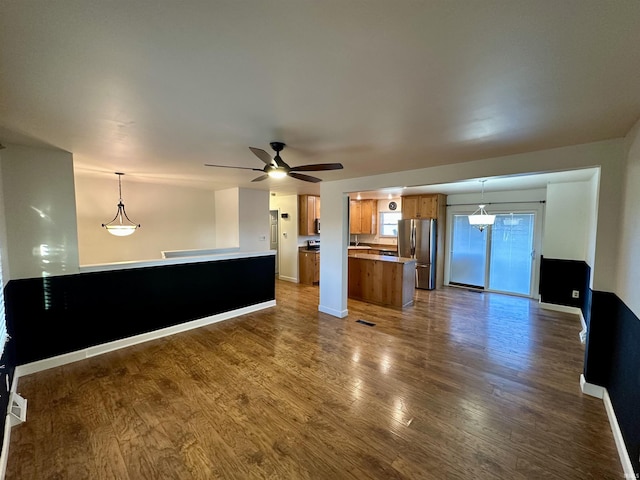 kitchen featuring dark wood-type flooring, open floor plan, freestanding refrigerator, brown cabinetry, and a ceiling fan