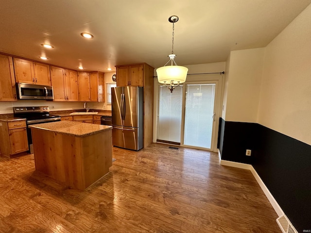 kitchen with dark wood finished floors, decorative light fixtures, recessed lighting, appliances with stainless steel finishes, and a sink