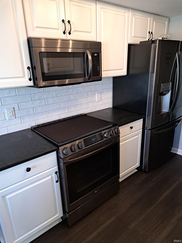 kitchen with stainless steel appliances, dark wood-type flooring, dark countertops, and white cabinets