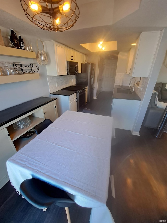 kitchen with a sink, black appliances, decorative backsplash, white cabinetry, and dark wood-style flooring