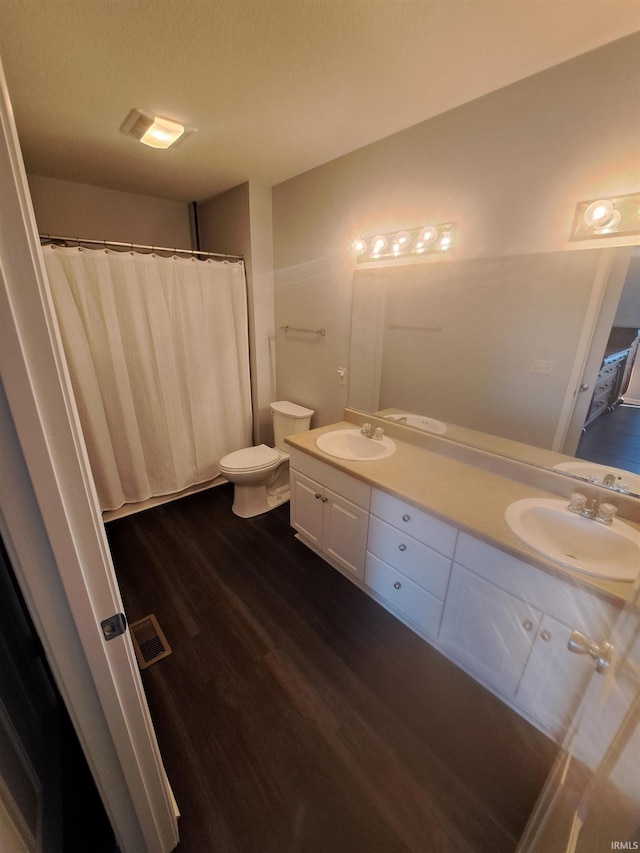 full bathroom with double vanity, wood finished floors, visible vents, and a sink