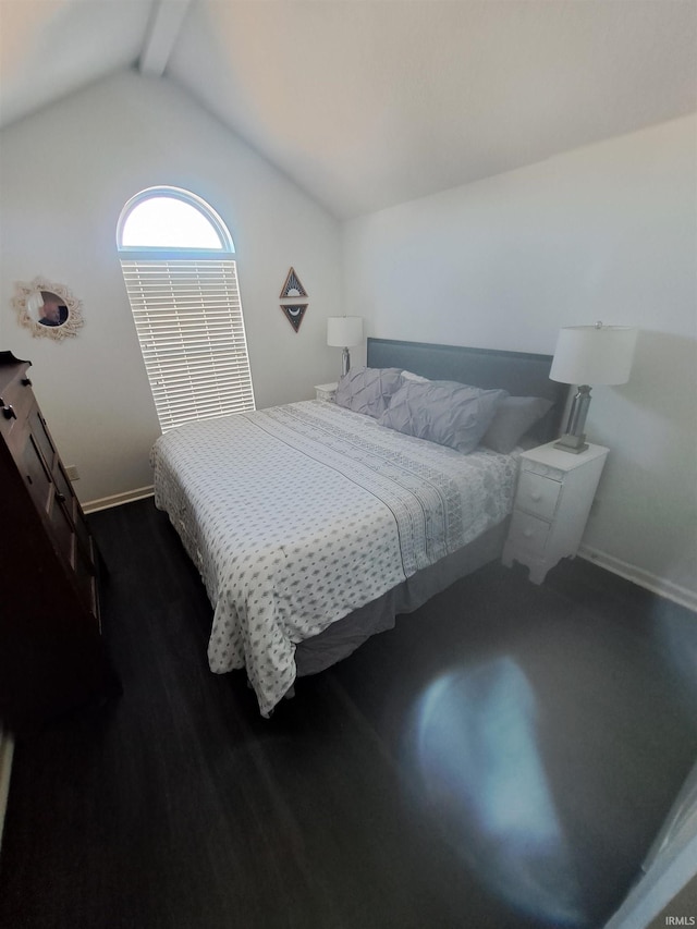 bedroom featuring lofted ceiling with beams, wood finished floors, and baseboards