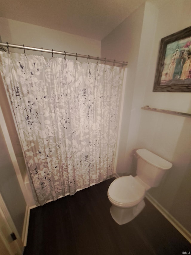 full bath featuring curtained shower, baseboards, toilet, and wood finished floors