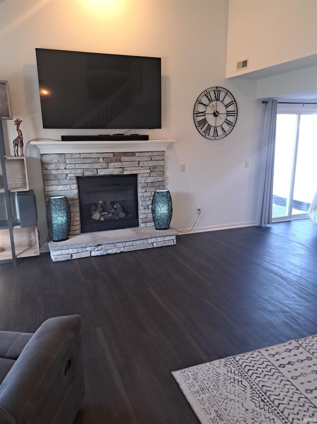 living area with visible vents, a fireplace, baseboards, and wood finished floors