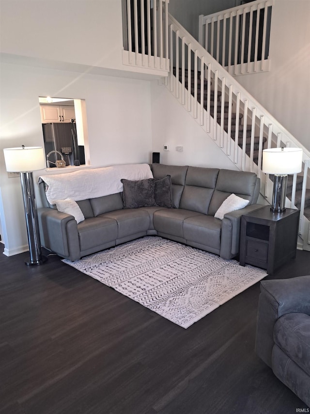 living room with a high ceiling, stairs, baseboards, and wood finished floors