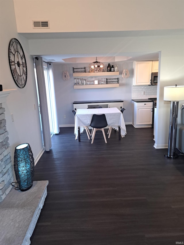 dining space featuring dark wood-style floors, visible vents, and baseboards