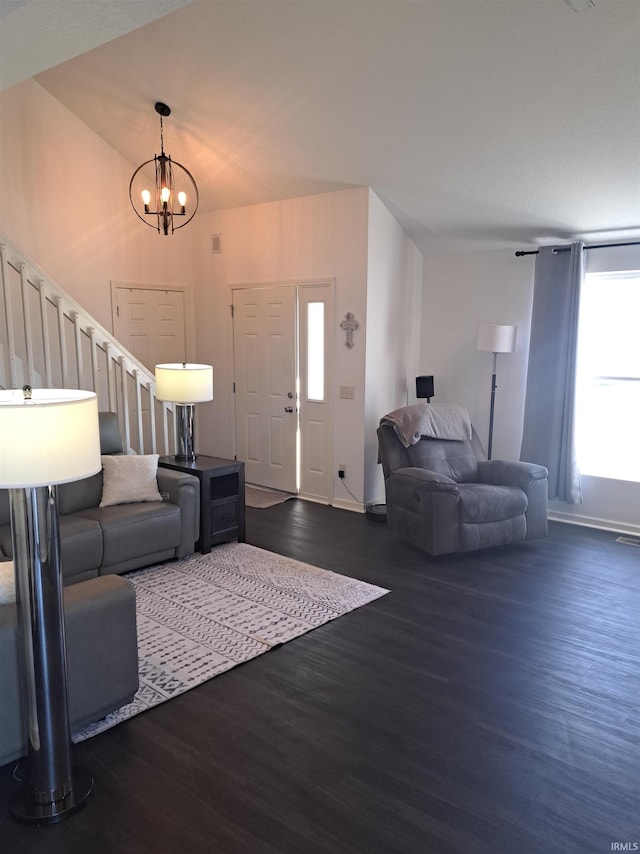 living room featuring a notable chandelier, baseboards, dark wood-type flooring, and stairs