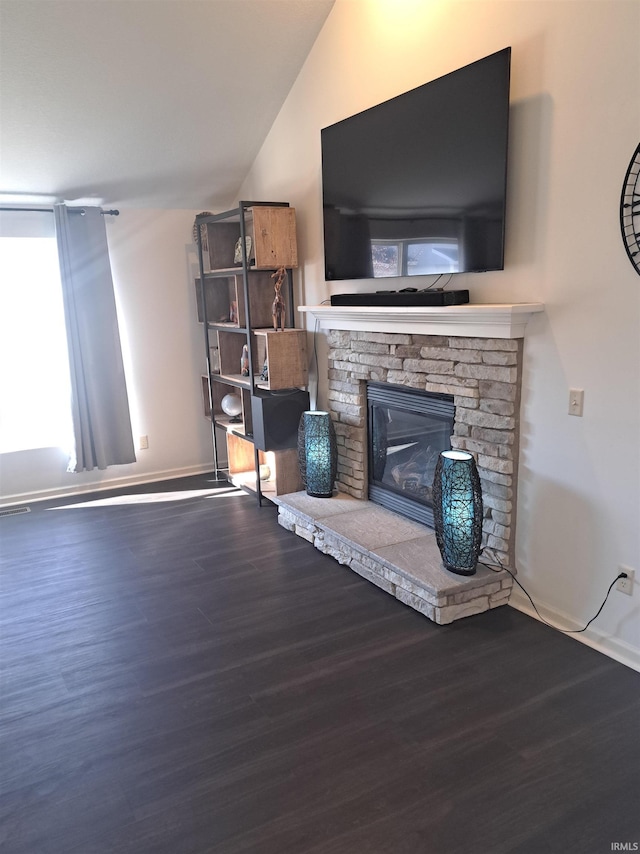 unfurnished living room with vaulted ceiling, a fireplace, baseboards, and wood finished floors