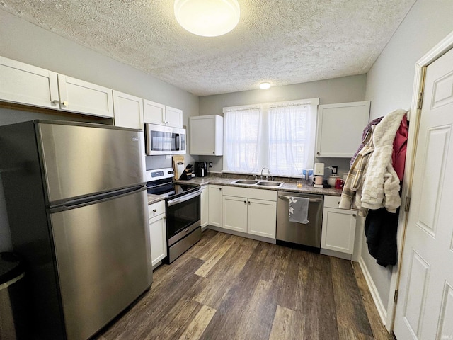 kitchen with dark wood-type flooring, stainless steel appliances, white cabinets, a textured ceiling, and a sink