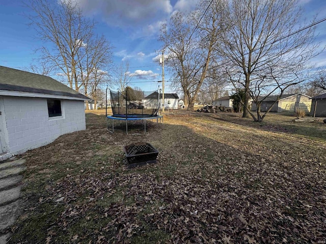 view of yard with a trampoline and an outdoor fire pit