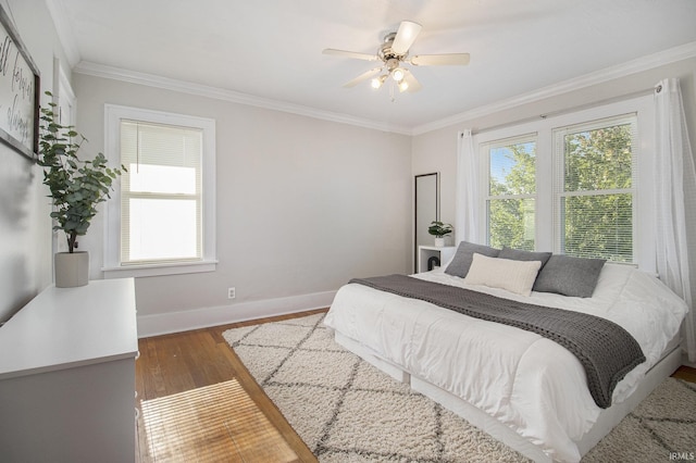 bedroom featuring crown molding, wood finished floors, baseboards, and ceiling fan